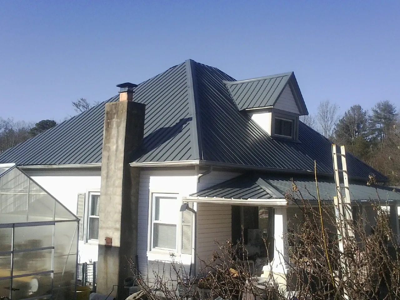 Dark blue standing seam metal roof on a white farmhouse with dormer — Slate & Tile Roof Repair by Roofing Brothers in Bemidji