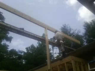 Carpenter setting a ridge beam over a new addition frame — Ice Dam Removal by Roofing Brothers in Bemidji