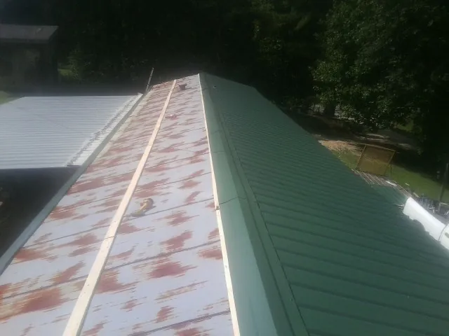 Old rusted panels beside newly installed green metal roofing — Wind Damage Roof Repair by Roofing Brothers in Bemidji